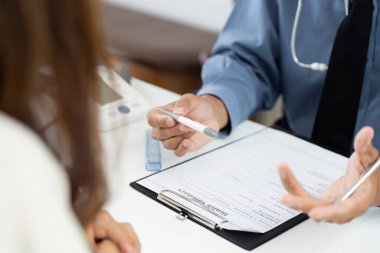 Bir doktor, sağlık sonuçlarını hastaya açıklar, tıbbi danışmanlıklarda iletişimi ve anlayışı vurgular.