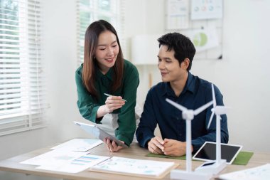 Bir rüzgar türbini modeli etrafında tartışmaların yer aldığı yenilenebilir enerji projelerine odaklanan stratejik bir toplantı.