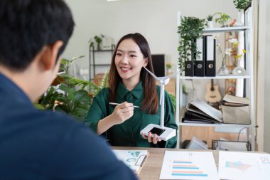Meslektaşlar sürdürülebilir enerji stratejileri üzerinde işbirliği yaparak, kavramları göstermek için bir rüzgar türbini modeli kullanırlar.