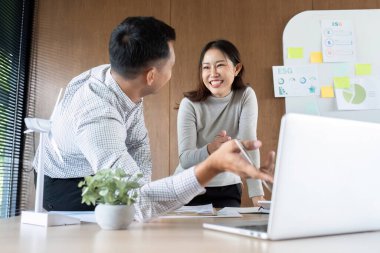 İki meslektaş gülümseyip ESG stratejileri hakkında fikir alışverişinde bulunurken, sürdürülebilirlik modellerini parlak bir çalışma alanında inceliyor.