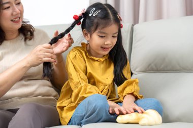Bir anne, kızlarının saçlarını birlikte eğlenirken şekillendirir. Evlerinde sevgi dolu bir atmosferi teşvik eder..