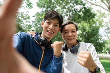 Bir baba ve oğul neşeli bir selfie çeker, güçlü bağlarını ve mutluluklarını doğal ortamlarında sergilerler..