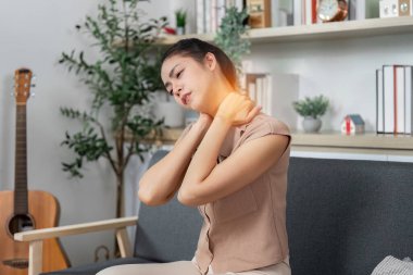 Bir kadın, rahat bir yuva ortamındaki rahatsızlığı yansıtan acılar içinde boynunu tutar. Sağlığa ve sağlığa odaklan..