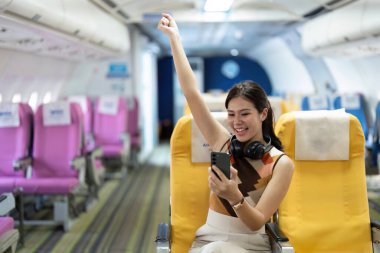 Uçuşta keyifli bir gezgin, seyahatini el kaldırarak ve akıllı bir telefonla kutluyor, anı yakalıyor..