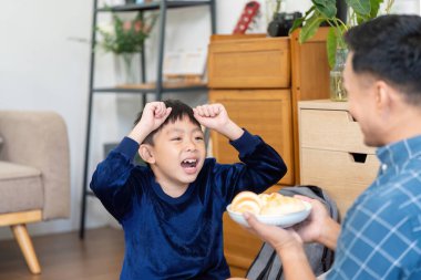 Mutlu bir çocuk, babasından bir tabak abur cubur alırken sevinç ve coşku gösterir. Aile bağında bir anlık mutluluğu ön plana çıkarır..