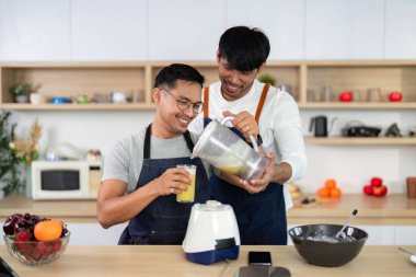 İki arkadaş, neşeli ve sağlıklı bir yaşam tarzını sergilemek için parlak bir mutfakta smoothie yapmaktan hoşlanırlar..