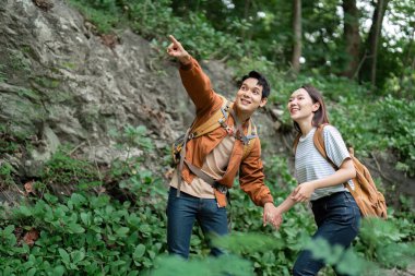Bir çift, doğa manzarasına işaret ederek ve birlikte doğanın güzelliğinin tadını çıkararak yürüyüş yaparken bir neşe anı paylaşır..