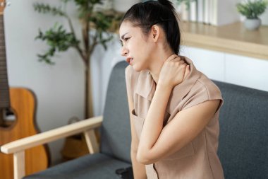 Genç bir kadın, günlük yaşamda sağlık ve sağlığın önemini yansıtan bir rahatsızlıkla boynunu tutuyor..