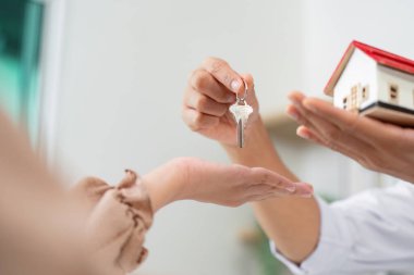 Müşteri, emlakçıdan anahtar ve minyatür bir ev alır. Bu da emlak alımındaki son adımı belirler..