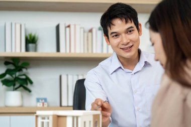 Bir emlakçı, modern ofis ortamında mülkiyet detaylarını ve seçenekleri açıklayan bir müşteriyle ilişki kurar..