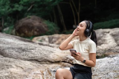 Bir kadın, sakin bir açık hava ortamında müzik dinlerken, doğa ve en sevdiği melodileri dinlerken rahatlar..