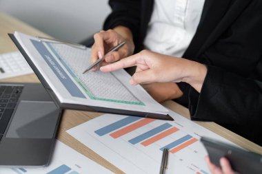 Finansal raporları ve verileri yakından inceleyen iki iş kadını, analitik beceriler ve takım çalışmasını vurguluyor.