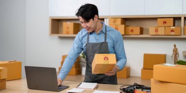 Merkez büroda paketleri dikkatlice hazırlayan genç bir adam e-ticaret operasyonlarında verimliliği vurguluyor..