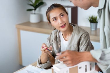 Mimarlar bir yapı modeli hakkında görüşlerini ve fikirlerini paylaşıyorlar, işbirliğini ve yeniliği vurguluyorlar.