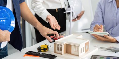 Çeşitli bir ekip sürdürülebilir mimari üzerinde işbirliği yaparak, minyatür bir yapı modeli ve rüzgar türbini analiz ederek, çevre dostu tasarımı destekliyor..