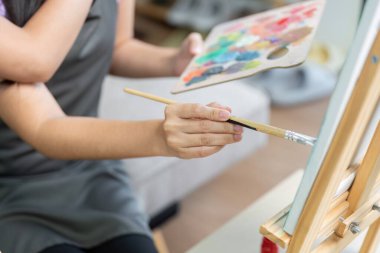 Bir çift, birlikte resim yaparken neşeli bir anı paylaşıyor. Yaratıcılıklarını ve sevgilerini samimi bir stüdyoda sergiliyorlar..