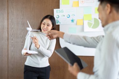 Bir ekip üyesi sürdürülebilirlik girişimlerini vurgulayan ve iş arkadaşlarını tartışmaya sokan yenilenebilir bir enerji modeli sunar.