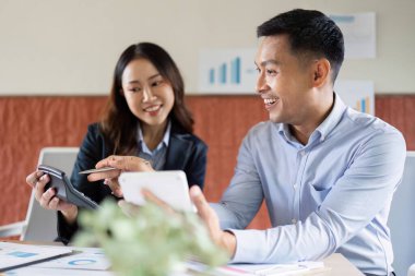 Dijital cihazlar üzerindeki çizelge ve analizleri inceleyen iki profesyonel, takım çalışmasının ve üretkenliğin geliştirilmesi.