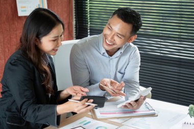 Bir kadın ve erkek, ofis ortamında verileri incelerken fikir alışverişinde bulunup fikir alışverişinde bulunuyorlar..