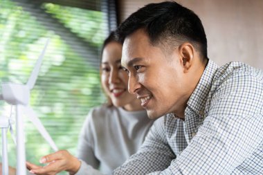 Modern bir çalışma alanında sürdürülebilirlik ve yenilikçi tasarımı vurgulayan rüzgar enerjisi projeleri üzerinde çalışan iki profesyonel.