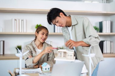 Bir çift mimar, takım çalışmasını ve yenilikleri vurgulayarak çevre dostu bir proje için bir model oluşturuyorlar..