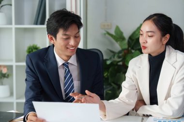 Çağdaş bir ofis ortamında proje belgelerini analiz eden iki iş adamı ortak bir tartışmaya giriştiler..