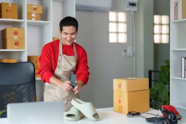 Genç bir girişimci akıllı telefonuyla ürün görüntülerini yakalıyor ve online iş varlığını geliştiriyor..