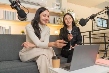 İki kadın canlı bir podcast tartışmasına girişiyor, modern bir stüdyo ortamında kapsayıcılık ve bağlantı sergiliyorlar..