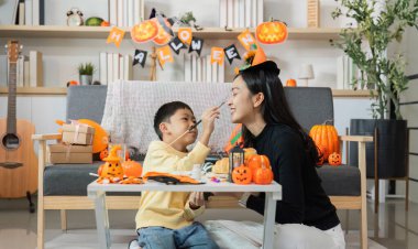 Bir anne ve oğul cadılar bayramı zanaatı ile meşgul, süslerle ve balkabaklarıyla çevrili, bayram ruhunu kutluyorlar..