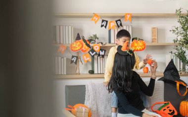 Bir anne ve oğlu, Cadılar Bayramı temalı dekorlarla çevrili bir şekilde neşe dolu bir şekilde etkileşime geçerek yaşam alanlarında neşeli anılar yaratıyorlar..