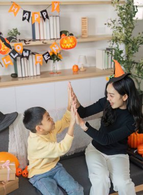 Bir anne ve oğlu arasında neşeli bir an, Cadılar Bayramı 'nı kostümlerle ve şenlikli dekorasyonlarla kutluyor..