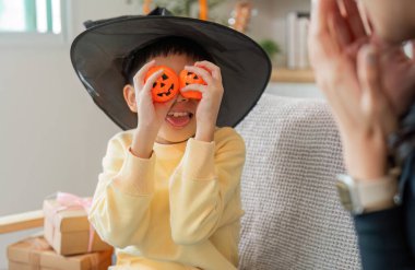 Cadı şapkalı oyuncu bir çocuk Cadılar Bayramı süslemeleri taşıyor, neşeli bir atmosferde yaratıcılık ve neşe ifade ediyor..