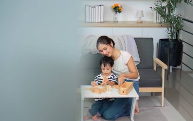 Bir anne ve çocuğu birlikte iyi vakit geçirmenin keyfini çıkarırlar. Sıcak ve davetkar bir yuva ortamında ahşap bloklar inşa ederler..