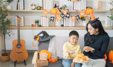 Bir anne ve oğlu, sıcak bir evde Cadılar Bayramı 'nı kutlarken lezzetli ikramları paylaşıyor..