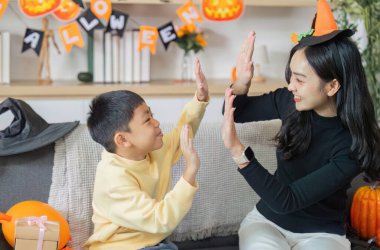 Süslemeler ve balkabaklarıyla çevrili neşeli anların tadını çıkaran bir anne ve oğul ile neşeli bir Cadılar Bayramı sahnesi..