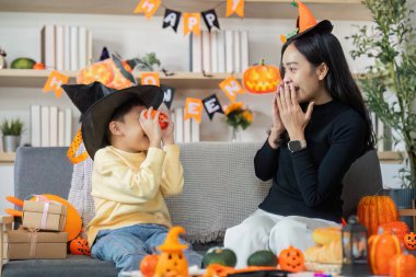 Neşeli bir Cadılar Bayramı sahnesi. Renkli dekorasyonlar arasında eğlenceli aktivitelere katılan bir anne ve oğul..