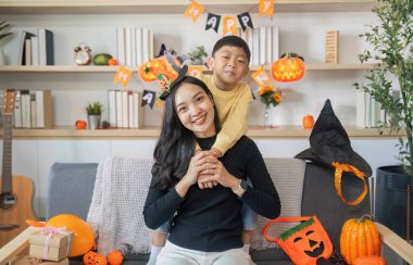 Renkli süslemelerle çevrili neşeli etkileşimlerin tadını çıkaran bir anne ve oğulla dolu iç açıcı bir Cadılar Bayramı sahnesi..