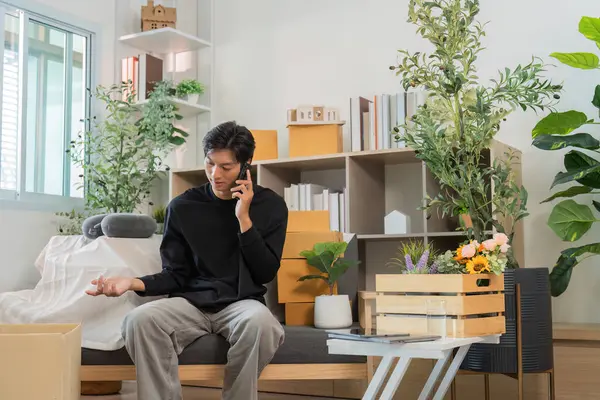 Genç bir adam, modern iletişimi yansıtan şık bir oturma odasında otururken bir telefon görüşmesi yapar..