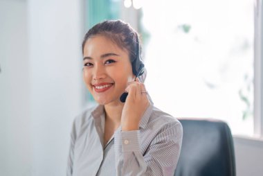 Neşeli bir kadın müşteri hizmetleri acentesi müşterilerine modern ofis ortamında yardım etmek için kulaklık kullanır..