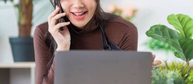 Bir kadın telefonda konuşuyor, evden fabrika işletmesini yönetirken gülümsüyor, uzaktan çalışmanın geleceğini gösteriyor..