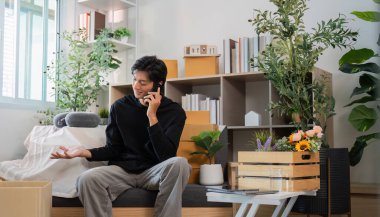 Genç bir adam, yeşil ve organize kutularla çevrili şık ev ofisinde telefon konuşmasından hoşlanıyor..