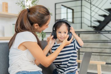 Bir anne oğluna kulaklık takması için yardım eder, oyun zamanları boyunca hoş bir bağlantı ve eğlence anı yaratır..