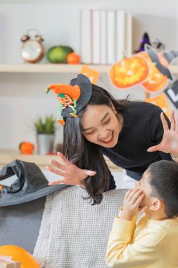 Bir anne ve oğul, Cadılar Bayramı süslemeleriyle çevrili neşeli bir etkileşimin keyfini çıkarırlar..