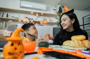 Bir anne ve oğlu, Cadılar Bayramı için evlerini dekore ederken neşeli bir anı paylaşıyorlar..