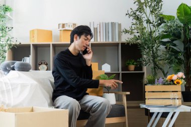 Genç bir adam, ofisinden canlı bir çiçek aranjmanına işaret eden bir telefon görüşmesi yapıyor..