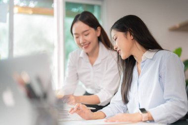 Modern bir ofis alanında işbirliği yapan iki profesyonel kadın, başarı için fikir ve stratejileri paylaşıyorlar..