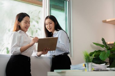 Meslektaşlar iş verilerini birlikte analiz ederler, modern bir çalışma alanında işbirliği ve etkili iletişim gösterirler.