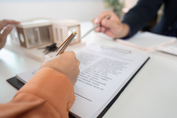 A client signs a real estate contract with an agent, emphasizing the commitment to a property purchase and professional guidance.