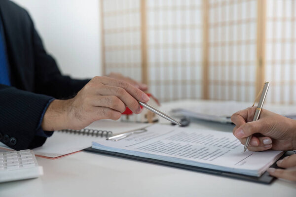 A real estate agent and client finalize an agreement, signing documents in a professional office setting.