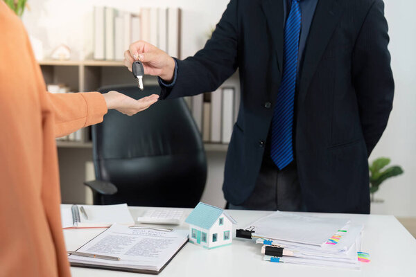 A real estate agent transfers keys to a buyer, marking the successful completion of a property ownership transfer.